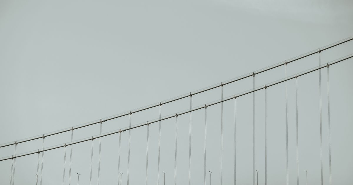 Suspension bridge cables against a pale sky